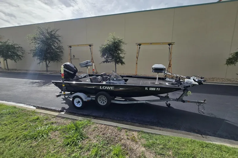 Slide: The Image of 2014 Lowe Stinger 18 HP boat on trailer, parked outdoors near a building. - 6