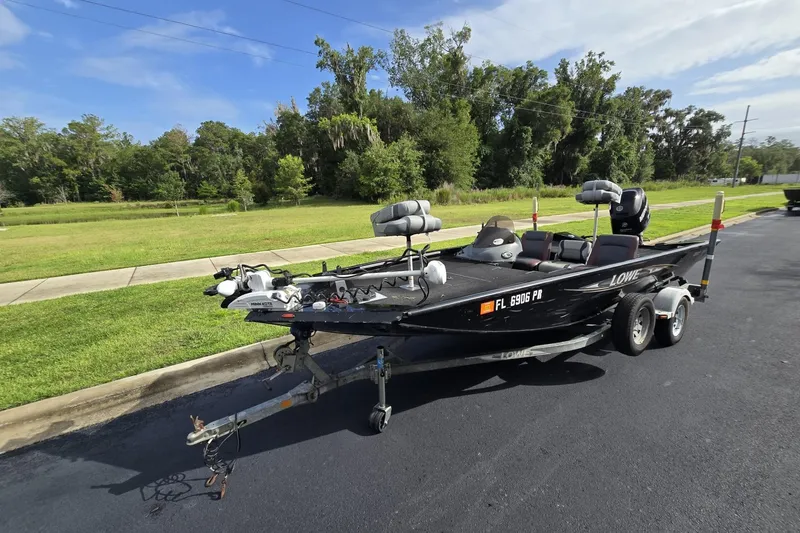 Slide: The Image of 2014 Lowe Stinger 18 HP boat on trailer, parked on asphalt near grassy area. - 3