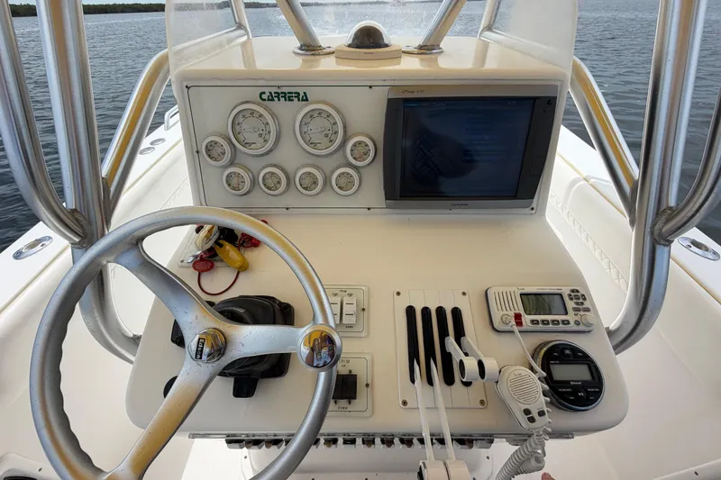 Slide: The Image of Center console of a 2004 Carrera Boats 27 CC Open, featuring steering wheel and navigation instruments. - 23