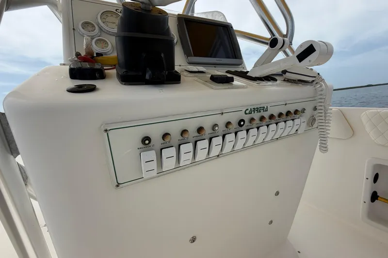 Slide: The Image of Control panel of a 2004 Carrera Boats 27 CC Open, featuring switches and gauges. - 27