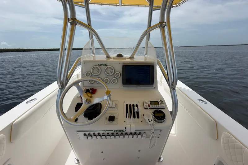 Slide: The Image of 2004 Carrera Boats 27 CC Open helm with steering wheel, gauges, and navigation equipment on open water. - 21
