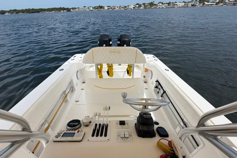 Slide: The Image of 2004 Carrera Boats 27 CC Open cockpit with steering wheel and controls, overlooking calm waters. - 28