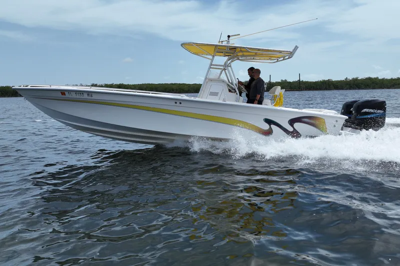 Slide: The Image of 2004 Carrera Boats 27 CC Open cruising on water, featuring vibrant graphics and dual Mercury engines. - 6