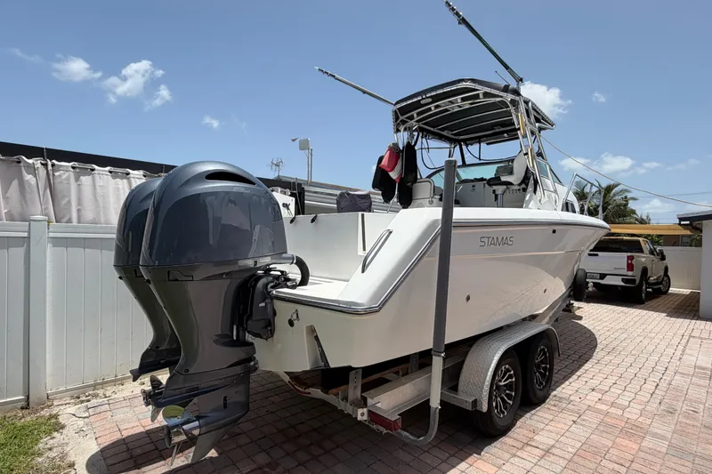 Slide: The Image of 2001 Stamas 270 Express boat on trailer, featuring dual outboard motors, parked in a driveway. - 5