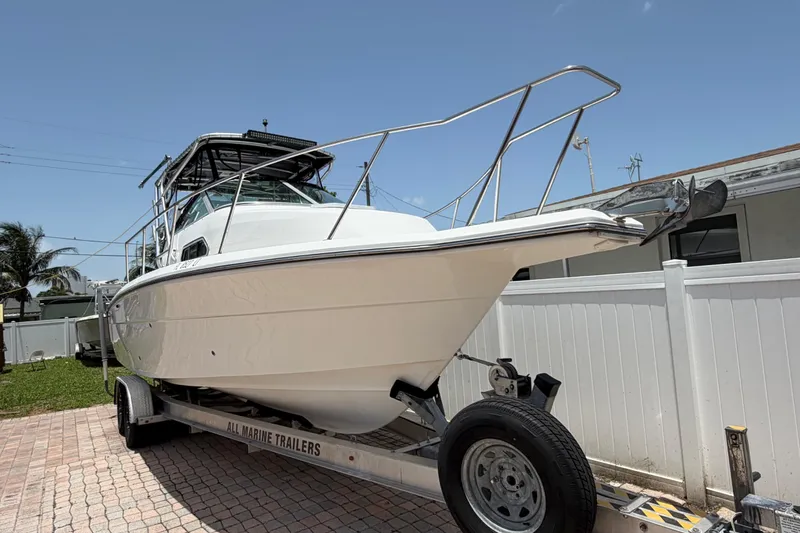 Slide: The Image of 2001 Stamas 270 Express boat on trailer, parked in a driveway under clear blue sky. - 4