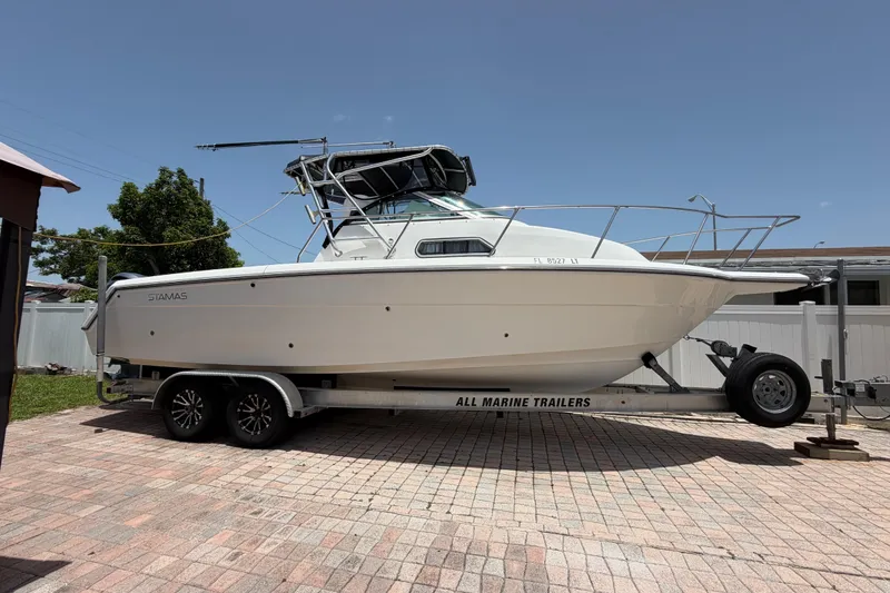 Slide: The Image of 2001 Stamas 270 Express boat on trailer, parked on brick driveway under clear sky. - 3