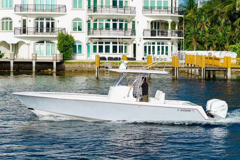 Slide: The Image of 2022 Contender 32 ST boat cruising near waterfront homes, showcasing sleek design and performance. - 12