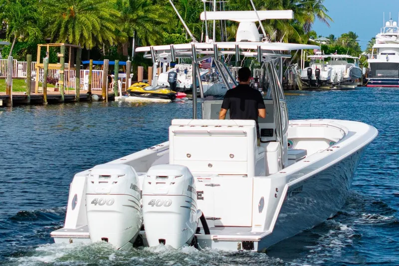 Slide: The Image of 2022 Contender 32 ST boat cruising on a scenic waterway with palm trees. - 1