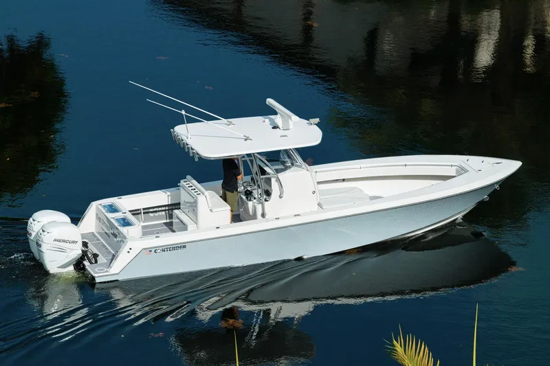 Slide: The Image of 2022 Contender 32 ST boat cruising on calm water with twin Mercury engines. - 5