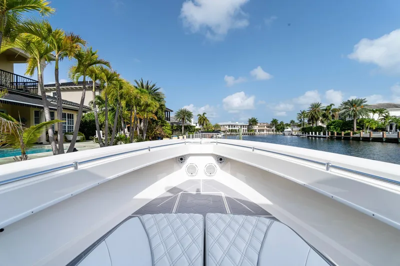 Slide: The Image of 2022 Contender 32 ST boat on a scenic waterfront with palm trees and blue sky. - 25
