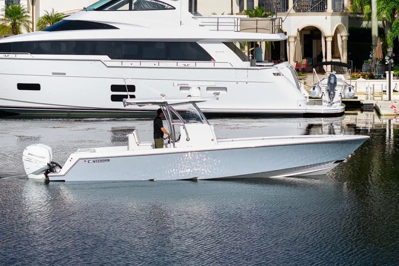 Slide: The Image of 2022 Contender 32 ST boat on water, docked near luxury yacht, sunny day. - 8