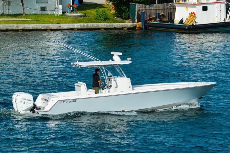 Slide: The Image of 2022 Contender 32 ST boat cruising on a sunny day with twin Mercury engines. - 18