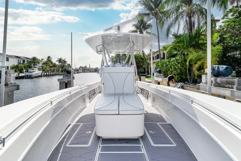 Slide: The Image of 2022 Contender 32 ST boat docked by a canal, surrounded by palm trees and clear skies. - 21