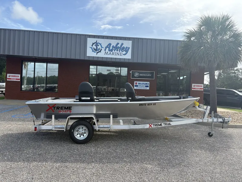 The Image of A silver XTREME BOATS Brute Series 1654 SS on a trailer in front of a building labeled "Ashley Marine." - 1