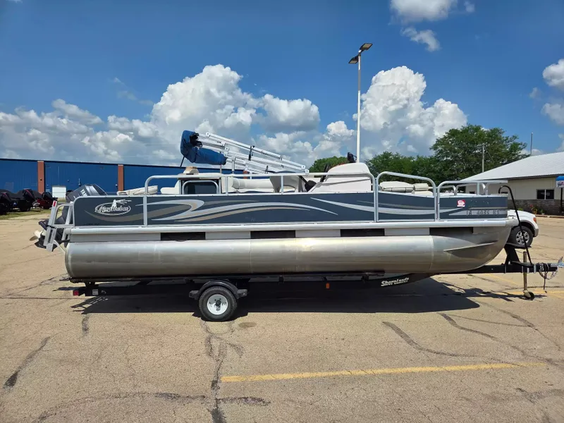 Slide: The Image of A 2010 Misty Harbor 2085 CF pontoon boat is on a trailer in a parking lot. - 1