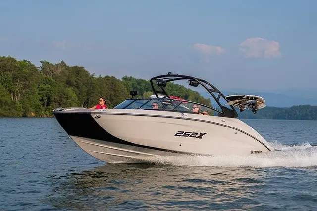 Slide: The Image of A modern Yamaha 252XE boat speeds across a calm lake, surrounded by green trees. - 13