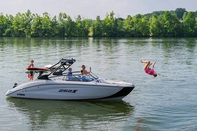 Slide: The Image of A Yamaha 252XE on a calm lake, with people enjoying themselves. One person is jumping into the water. - 14