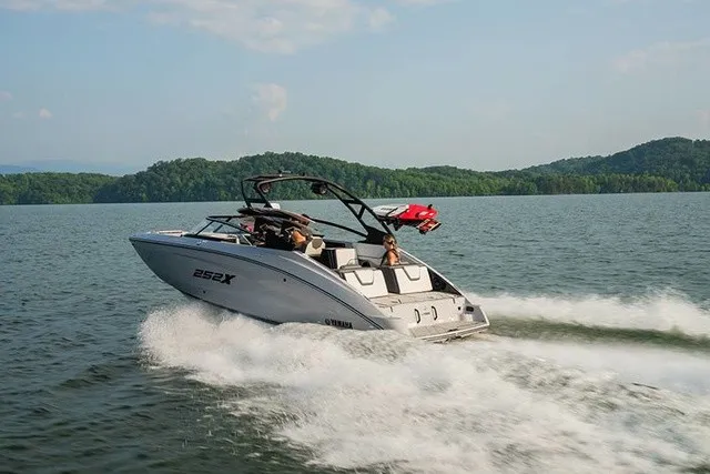 Slide: The Image of A modern Yamaha 252XE boat speeds across a calm lake, surrounded by green hills. - 15