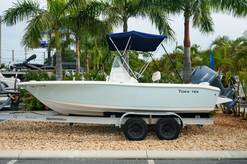 Slide: The Image of 2011 Tidewater 196 CC Adventure boat on trailer, surrounded by palm trees. - 2
