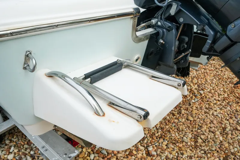 Slide: The Image of 2011 Tidewater 196 CC Adventure boat with swim platform and ladder on gravel. - 9