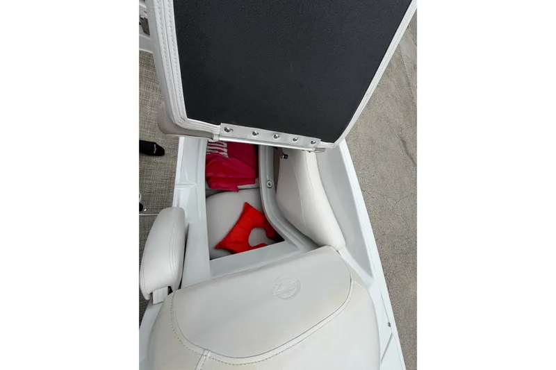 Slide: The Image of Open storage compartment in 2018 Crownline 285 SS boat, revealing life jacket and pink towel. - 19