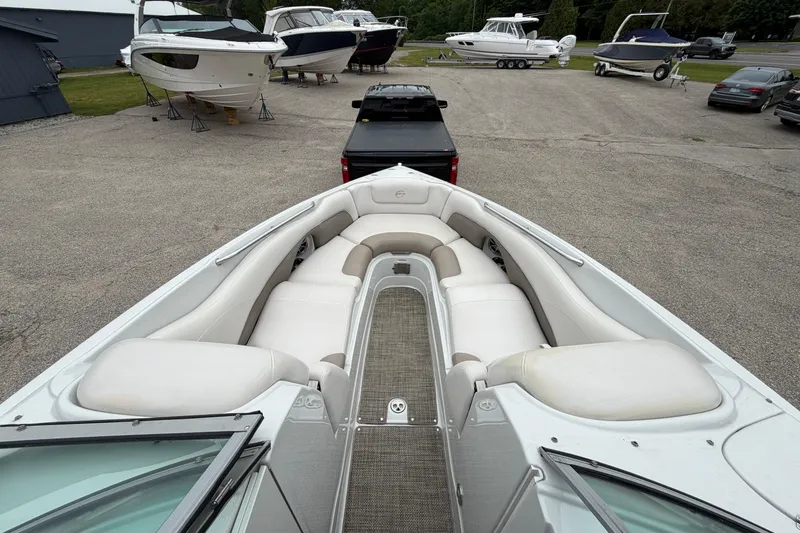 Slide: The Image of 2018 Crownline 285 SS boat with spacious seating, parked near other boats and vehicles. - 16