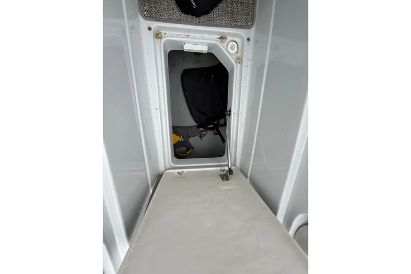 Slide: The Image of Storage compartment inside a 2018 Crownline 285 SS boat, featuring a hinged door and interior items. - 21