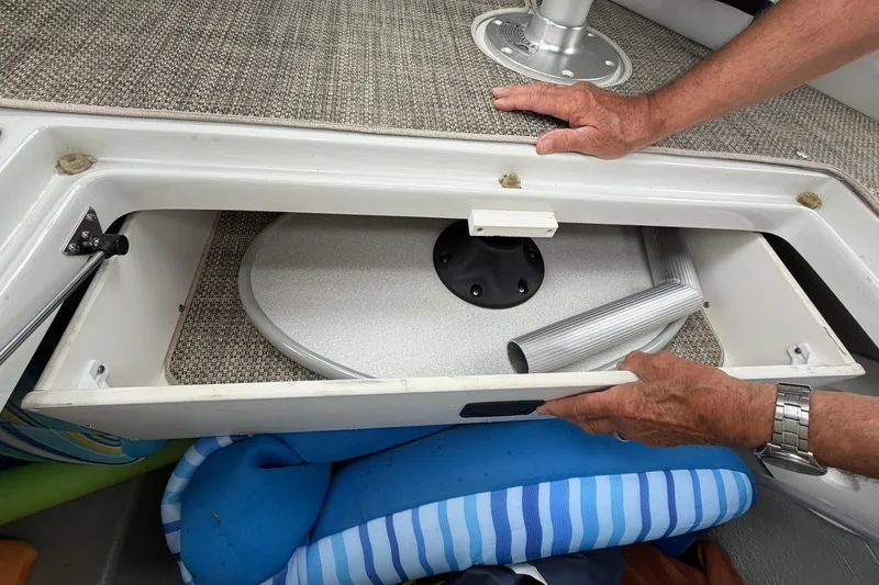 Slide: The Image of Storage compartment in a 2018 Crownline 285 SS boat with accessories and hands opening it. - 23