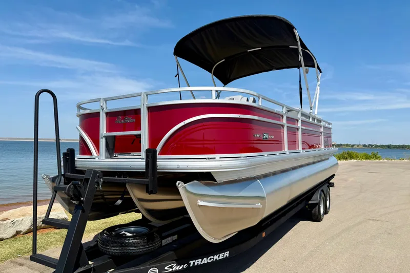 Slide: The Image of 2026 Sun Tracker Sportfish 24 XP3 pontoon boat on trailer by a lake. - 11