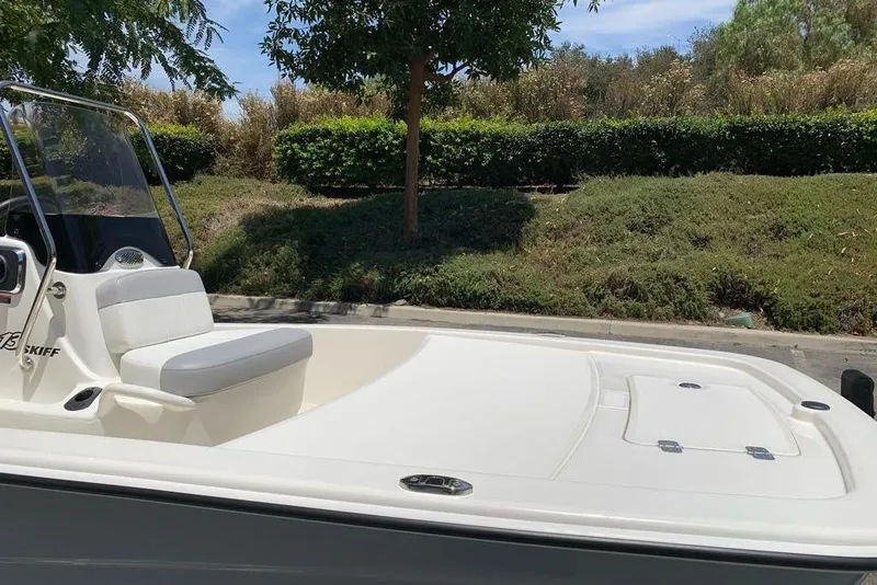 Slide: The Image of 2026 Mako Pro Skiff 13 CC boat with seating, parked near greenery. - 10
