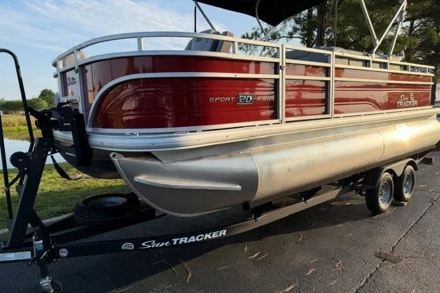 The Image of 2026 Sun Tracker SportFish 20 DLX pontoon boat on trailer, parked outdoors. - 0