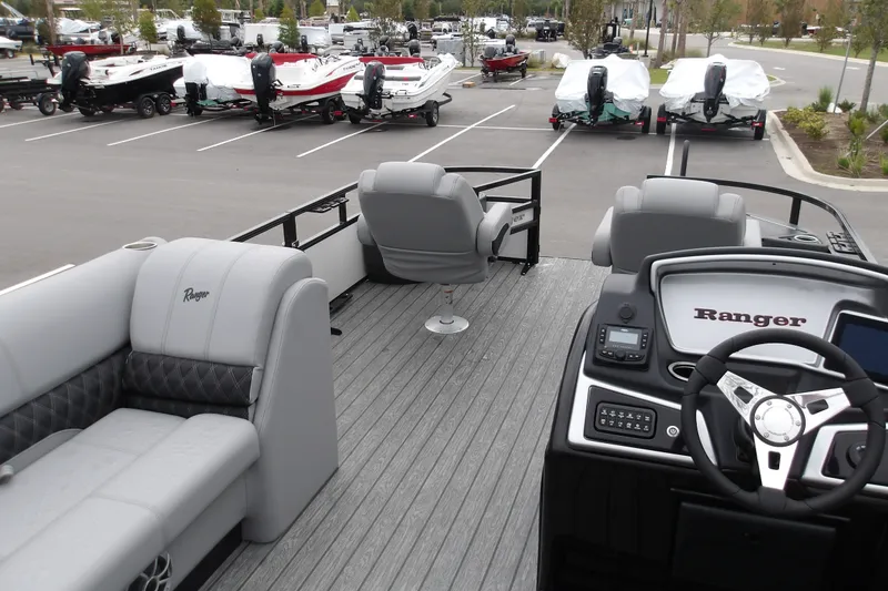 Slide: The Image of 2026 Ranger 220F pontoon boat interior with modern dashboard and seating in a parking lot. - 17
