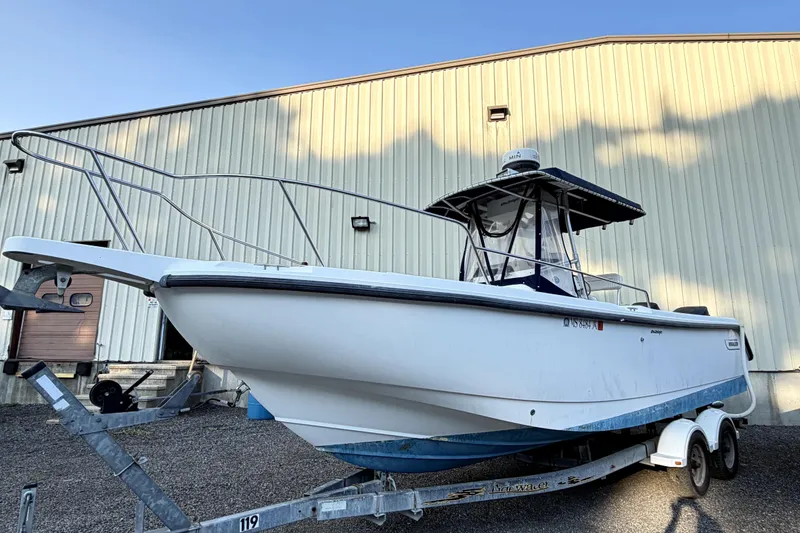 Slide: The Image of 2000 Boston Whaler 260 Outrage boat on trailer, parked near a warehouse. - 2