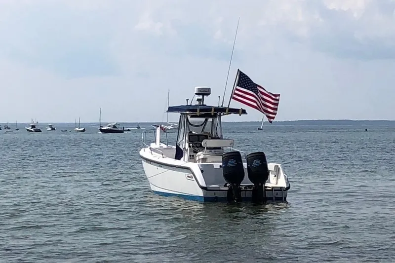Slide: The Image of Boston Whaler 260 Outrage boat with American flag on calm water, 2000 model. - 7