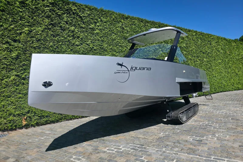 Slide: The Image of 2025 Iguana Commuter amphibious boat with tracks, parked on cobblestone path. - 2