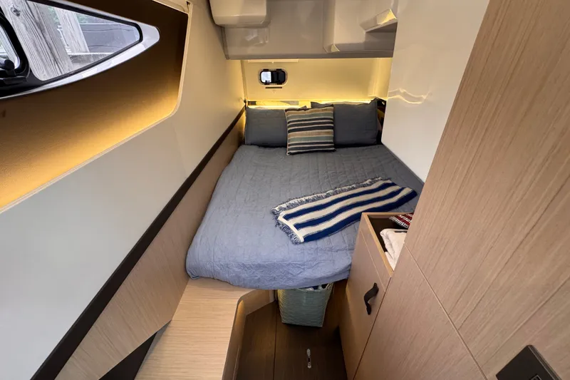 Slide: The Image of Cozy cabin interior of 2025 Four Winns TH36 boat with bed and striped blanket. - 32