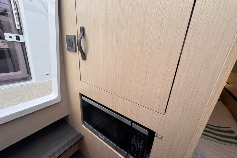 Slide: The Image of 2025 Four Winns TH36 interior with microwave and wooden cabinetry. - 24
