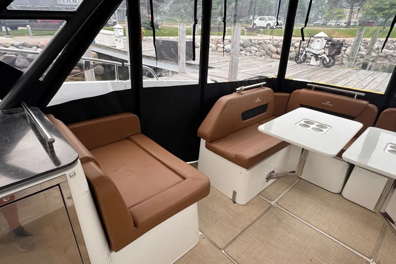 Slide: The Image of Interior of 2025 Four Winns TH36 boat with brown seating and white tables. - 16