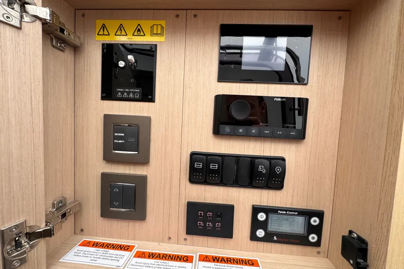 Slide: The Image of Control panel of 2025 Four Winns TH36 boat with various switches and warning labels. - 36