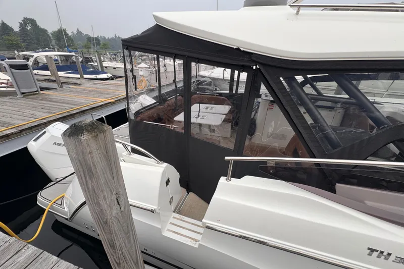 Slide: The Image of 2025 Four Winns TH36 boat docked at marina, featuring enclosed cabin and modern design. - 11