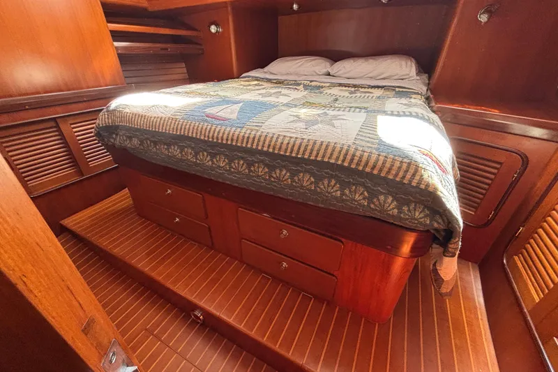Slide: The Image of Cozy cabin interior of 2002 Passport 470 Center Cockpit with wooden finish and quilted bedding. - 65