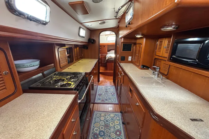 Slide: The Image of Interior of 2002 Passport 470 Center Cockpit yacht, featuring a well-equipped galley kitchen. - 55