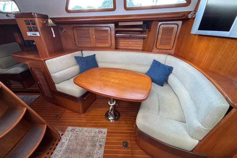Slide: The Image of Cozy interior of 2002 Passport 470 Center Cockpit with wooden table and cushioned seating. - 40