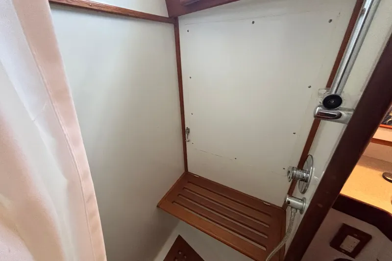 Slide: The Image of Interior of 2002 Passport 470 Center Cockpit shower with wooden bench and white walls. - 77