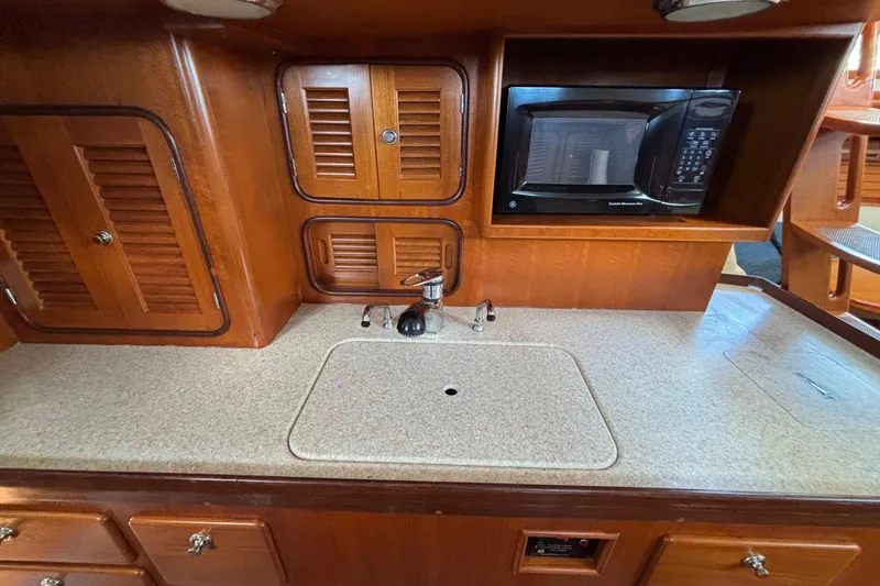Slide: The Image of Wooden yacht kitchen with sink, microwave, and storage cabinets in a 2002 Passport 470 Center Cockpit. - 58