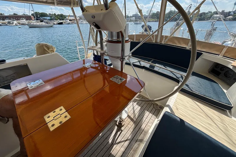 Slide: The Image of Cockpit of 2002 Passport 470 Center Cockpit sailboat with wooden table and steering wheel. - 22