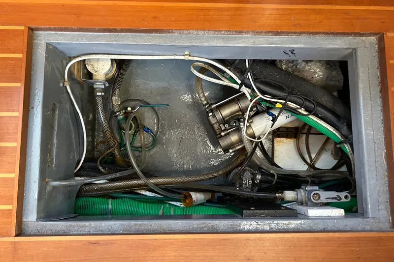 Slide: The Image of Engine compartment of a 2002 Passport 470 Center Cockpit sailboat, showing hoses and wiring. - 87