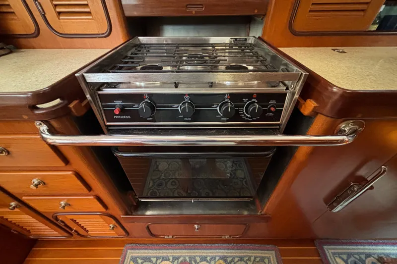Slide: The Image of 2002 Passport 470 Center Cockpit kitchen with stove and oven, featuring wooden cabinetry. - 61