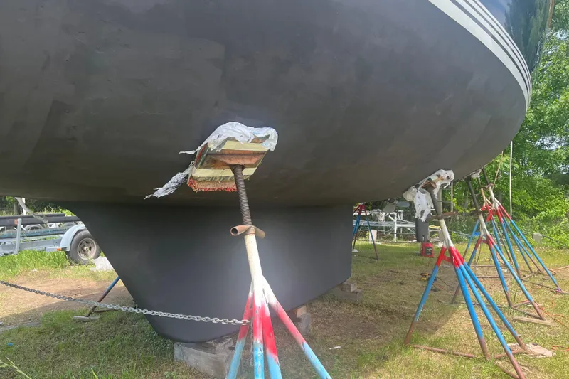 Slide: The Image of 2002 Passport 470 Center Cockpit sailboat on stands, undergoing maintenance on grassy area. - 89