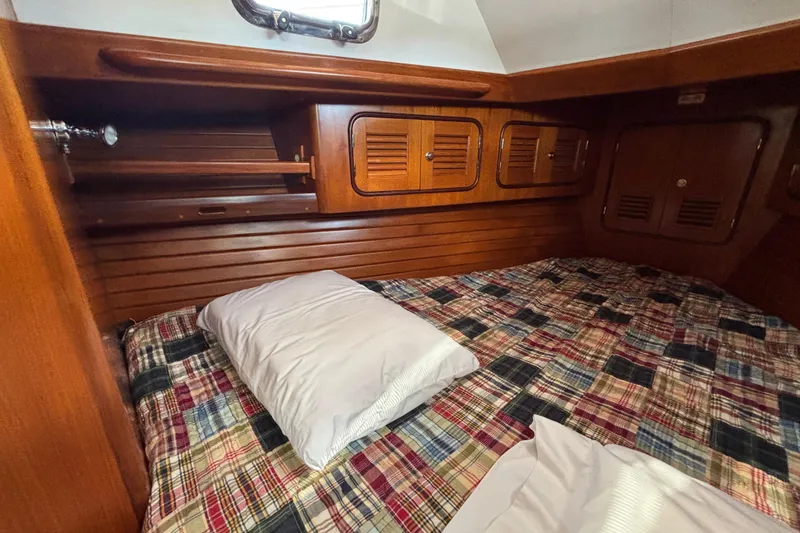 Slide: The Image of Cozy cabin interior of 2002 Passport 470 Center Cockpit with wooden storage and plaid bedding. - 74